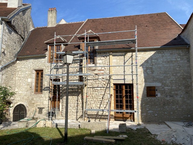 façade-pierre Artisan maçon sur un échafaudage rénovant un mur en pierre